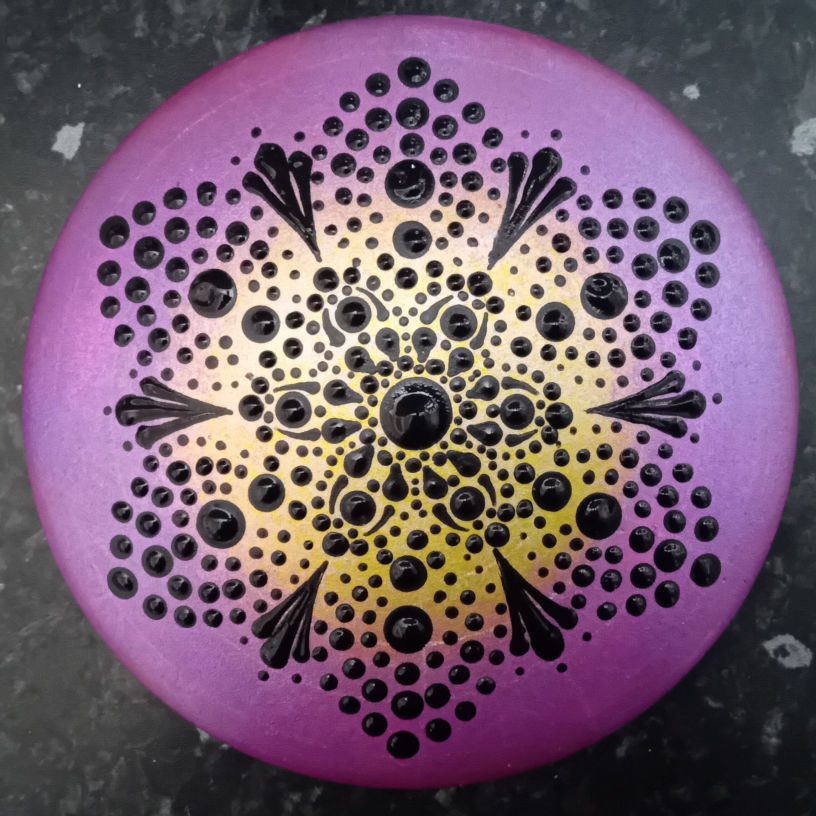 Decorative mandala with intricate black dot pattern on a gradient purple to yellow background, creating a floral mandala design. Vibrant and artistic.