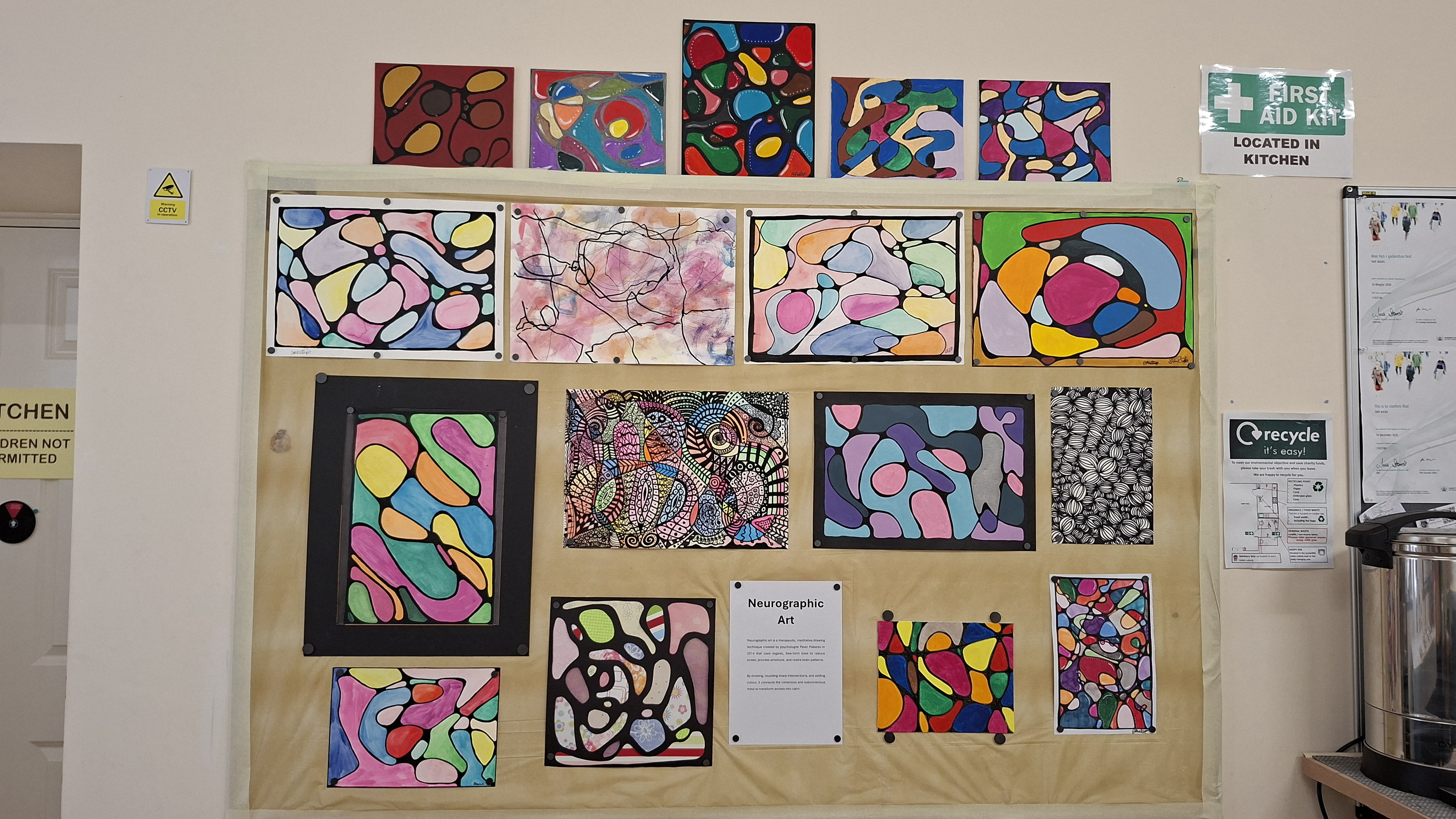 A display board showing colourful abstract neurographic art with swirling patterns, outlined shapes, and vibrant colours. The mood feels lively and creative.
