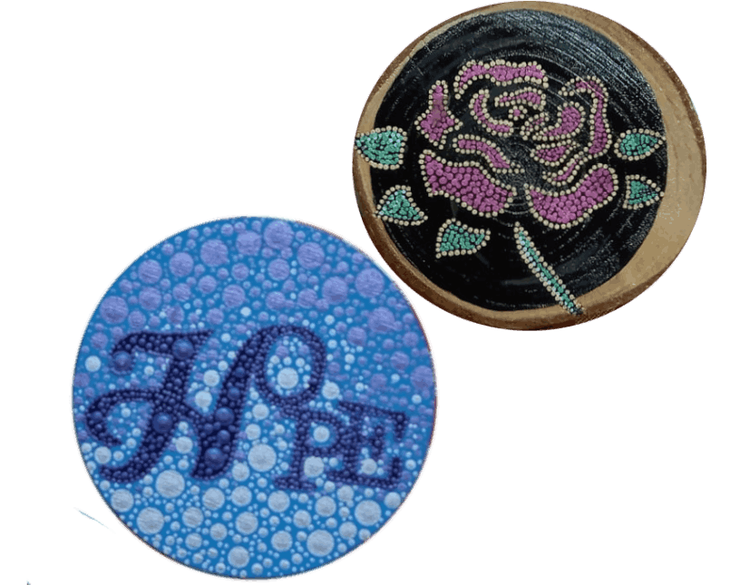 Two painted circular designs. One has Hope on a blue background with light dots. The other features a purple rose with green leaves on black.